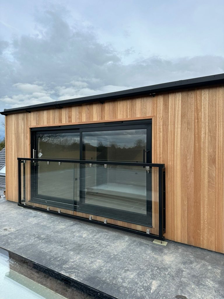 Black-framed glass Juliet balcony on a cedar-clad garden room