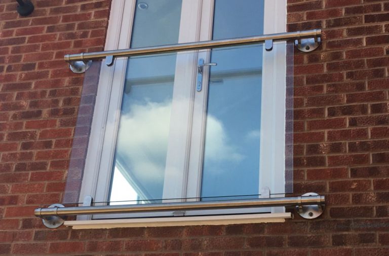 glass balcony against white doors on brick wall